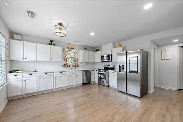 a large kitchen with cabinets wooden floor and stainless steel appliances