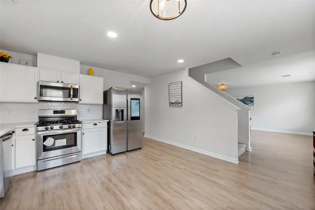 a kitchen with stainless steel appliances granite countertop a stove a sink dishwasher a refrigerator and a microwave oven with wooden floor