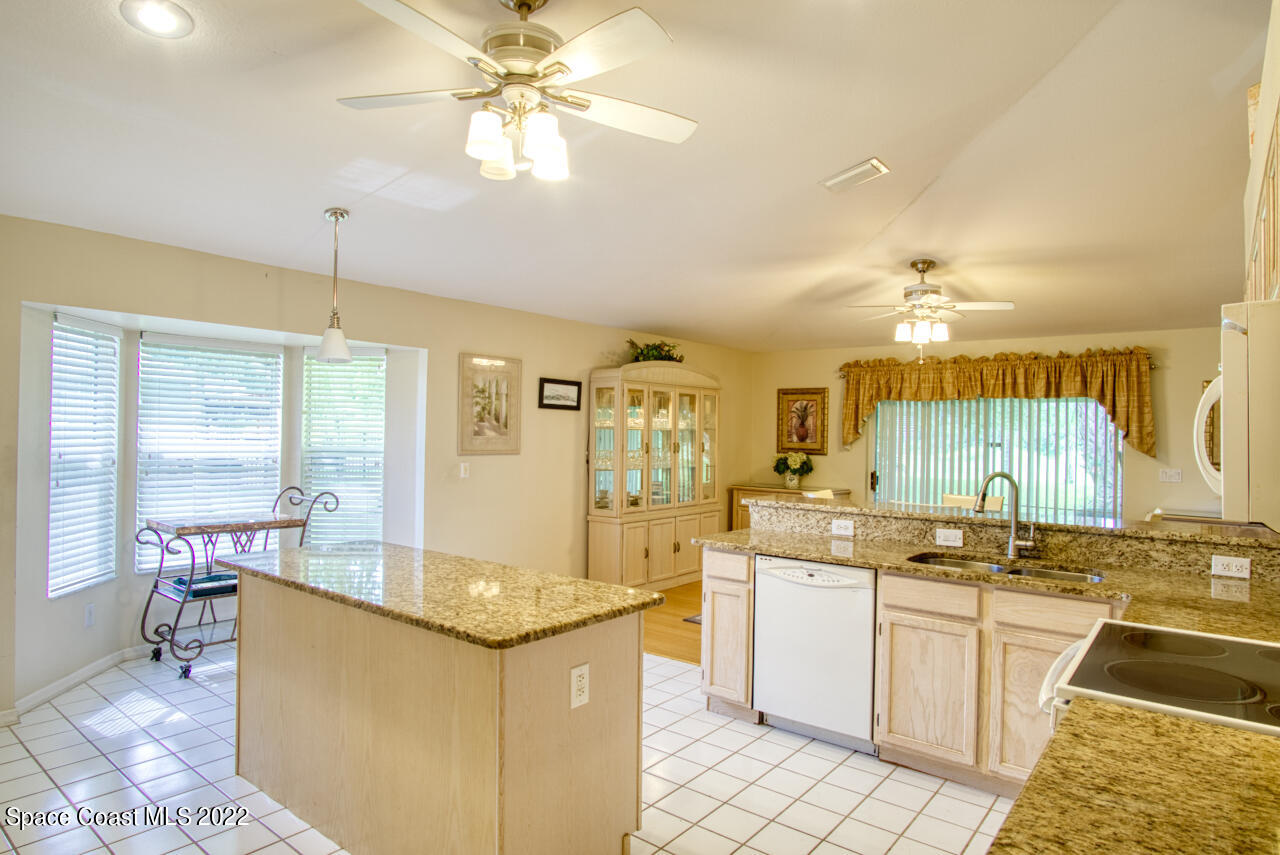 1190 Meadowbrook Road Northeast Palm Bay, FL 32905 - Photo 10 of 27 a kitchen with granite countertop a sink a stove top oven a dining table and chairs