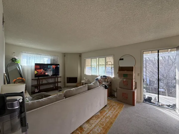 a living room with furniture a flat screen tv and a floor to ceiling window