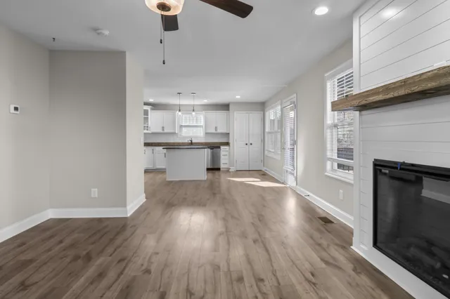 a view of an empty room with wooden floor fireplace and a window