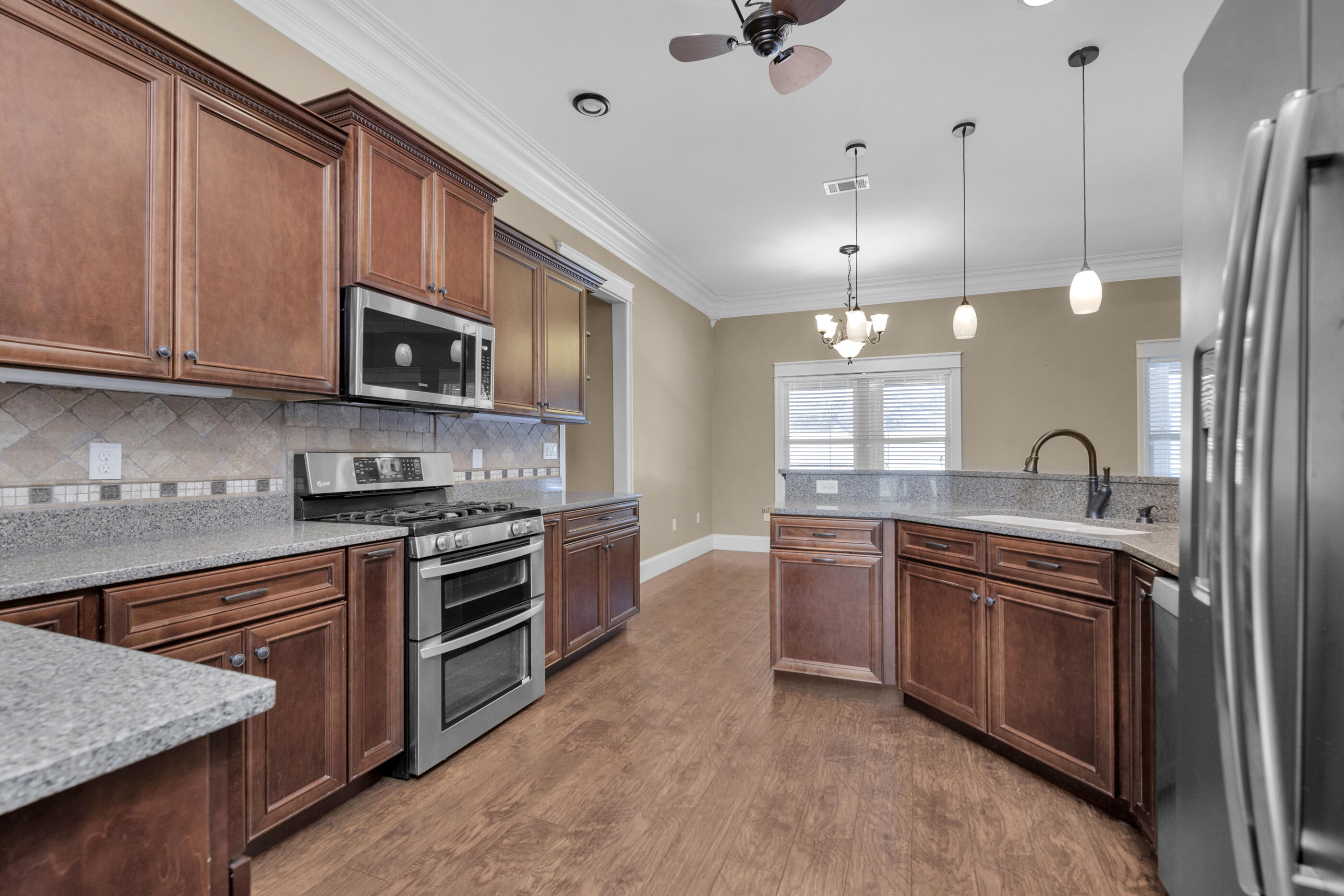5601 Old River Road Baker, FL 32531 - Photo 10 of 45 a large kitchen with stainless steel appliances granite countertop a stove a sink dishwasher and a microwave oven with white cabinets