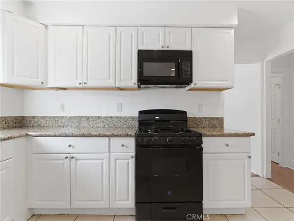 a kitchen with white cabinets and black appliances
