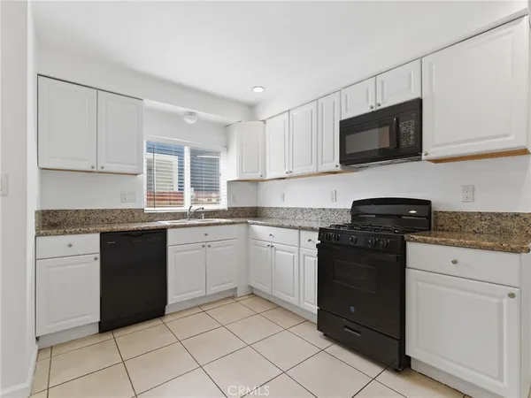 a white kitchen with granite countertop white cabinets and stainless steel appliances