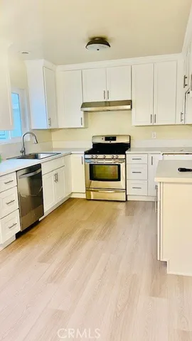 a kitchen with stainless steel appliances granite countertop a stove and white cabinets