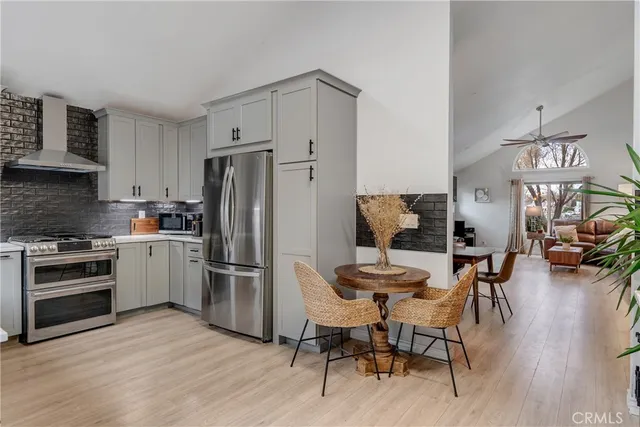 a kitchen with stainless steel appliances granite countertop a stove top oven a refrigerator a dining table and chairs with wooden floor