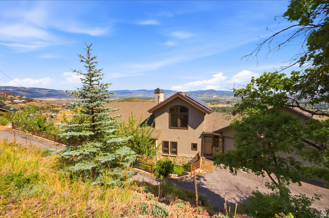 335 Bern Way Midway, UT 84049 - Photo 84 of 88 Hillside residence featuring a stucco and stone exterior, a pitched shingle roof, and a prominent chimney