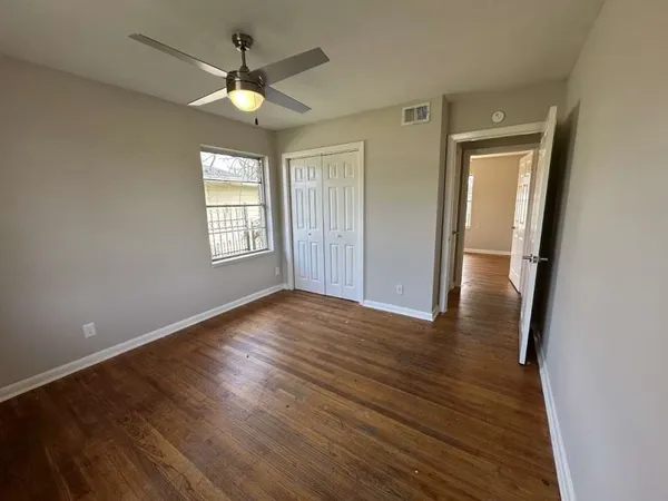 a view of an empty room with wooden floor and a window