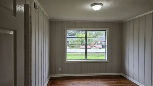 a view of an empty room with wooden floor and a window