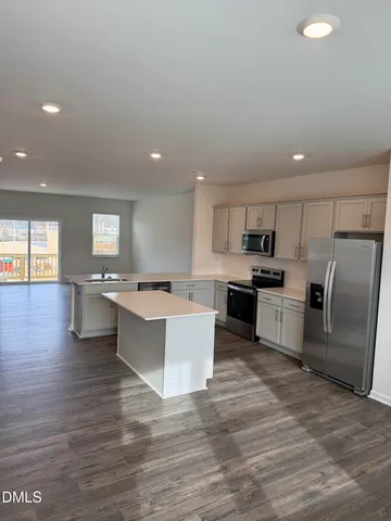 a large kitchen with stainless steel appliances a large counter top a stove a sink dishwasher and a refrigerator