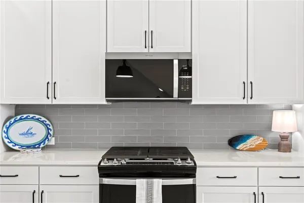a kitchen with granite countertop white cabinets and stainless steel appliances