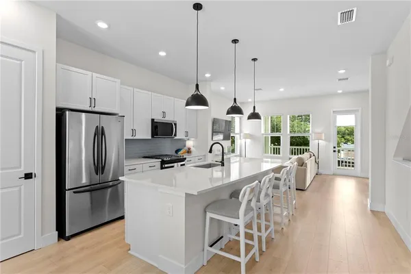 a kitchen with stainless steel appliances a refrigerator a stove a sink and white cabinets
