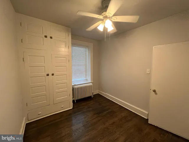 an empty room with wooden floor closet and windows