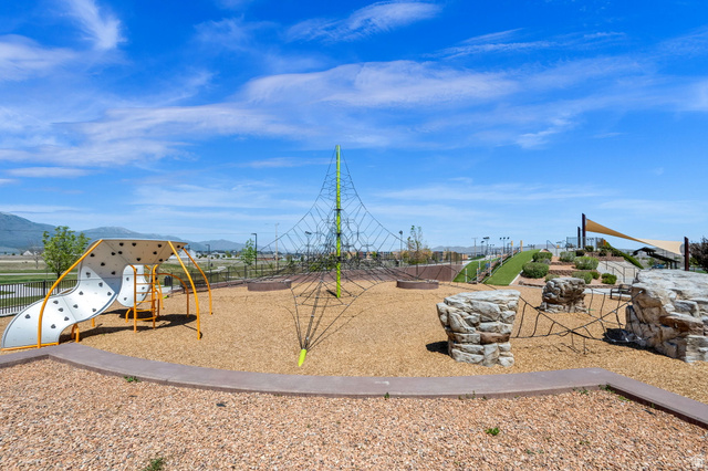 6120 North Sheps Ridge Road Eagle Mountain, UT 84005 - Photo 33 of 43 Community playground featuring varied play structures, a large climbing net, rock-like climbing elements, a slide, and a shade sail