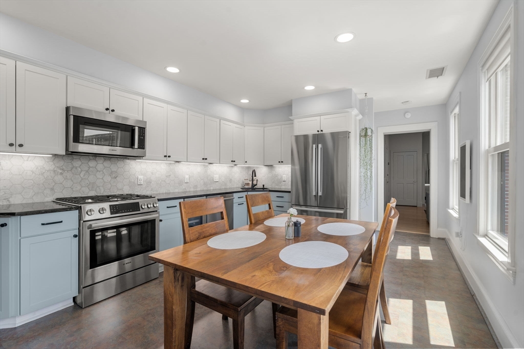 48 Mt Vernon Street, Unit 3 Boston, MA 02129 - Photo 7 of 31 a kitchen with stainless steel appliances granite countertop a stove a kitchen island a refrigerator a stove a microwave oven a dining table and chairs