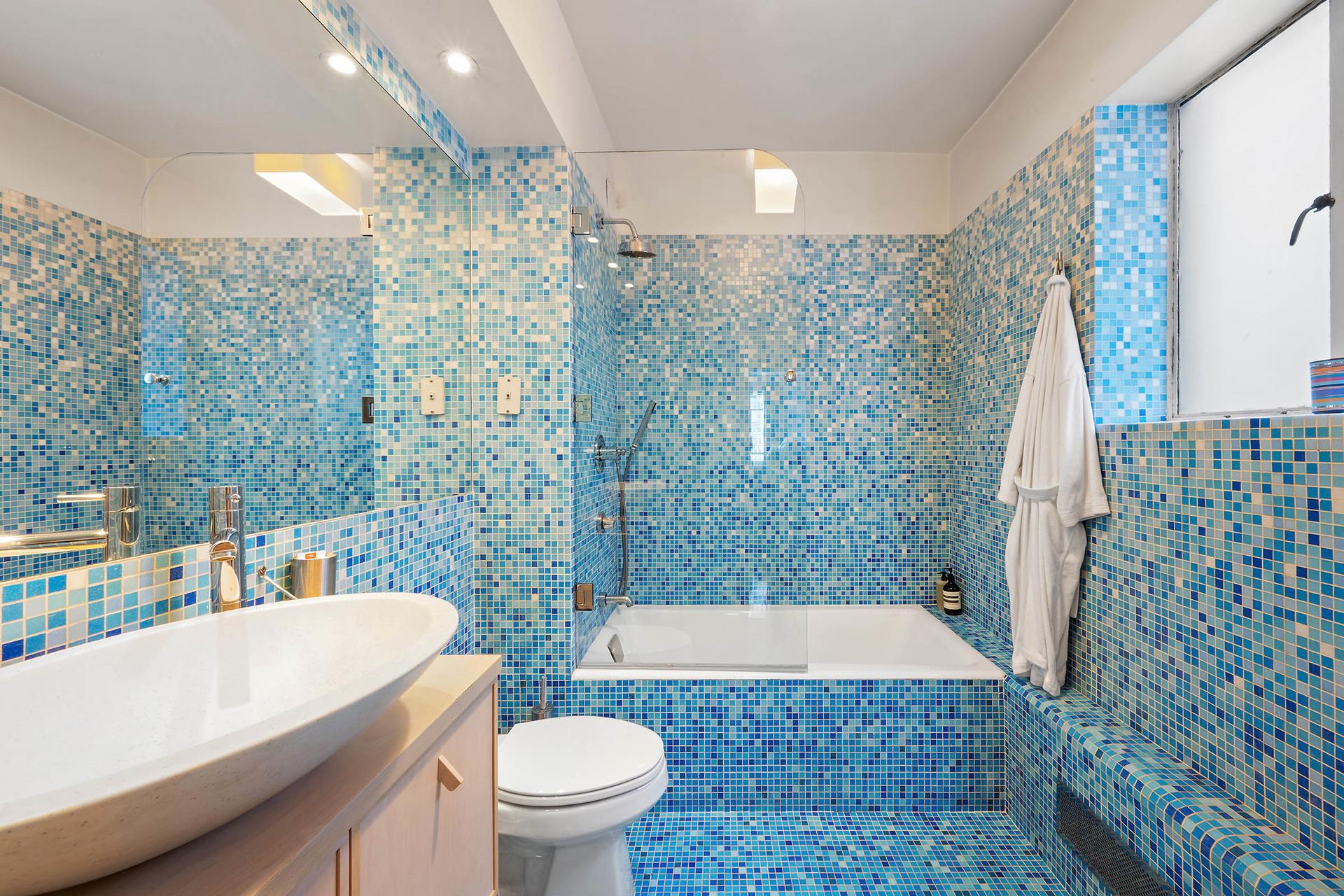 45 West 54th Street, Unit 11/12A Manhattan, NY 10019 - Photo 11 of 18 a bathroom with a sink a toilet a mirror a bathtub and shower