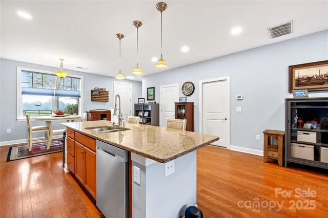 a kitchen with stainless steel appliances granite countertop a sink a stove and a wooden floors