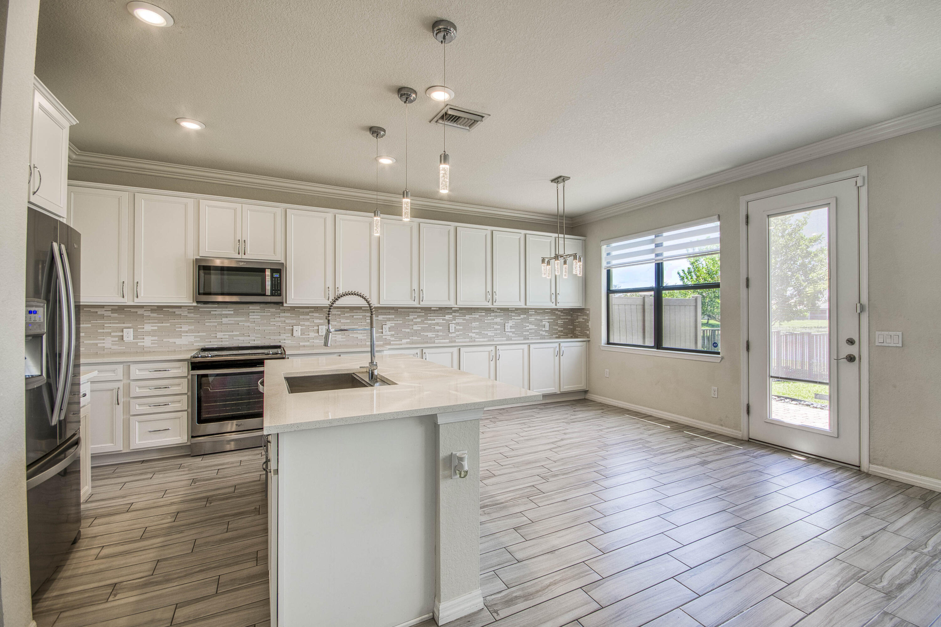8301 Rearing Lane Lake Worth, FL 33467 - Photo 11 of 33 a large kitchen with cabinets wooden floor and stainless steel appliances