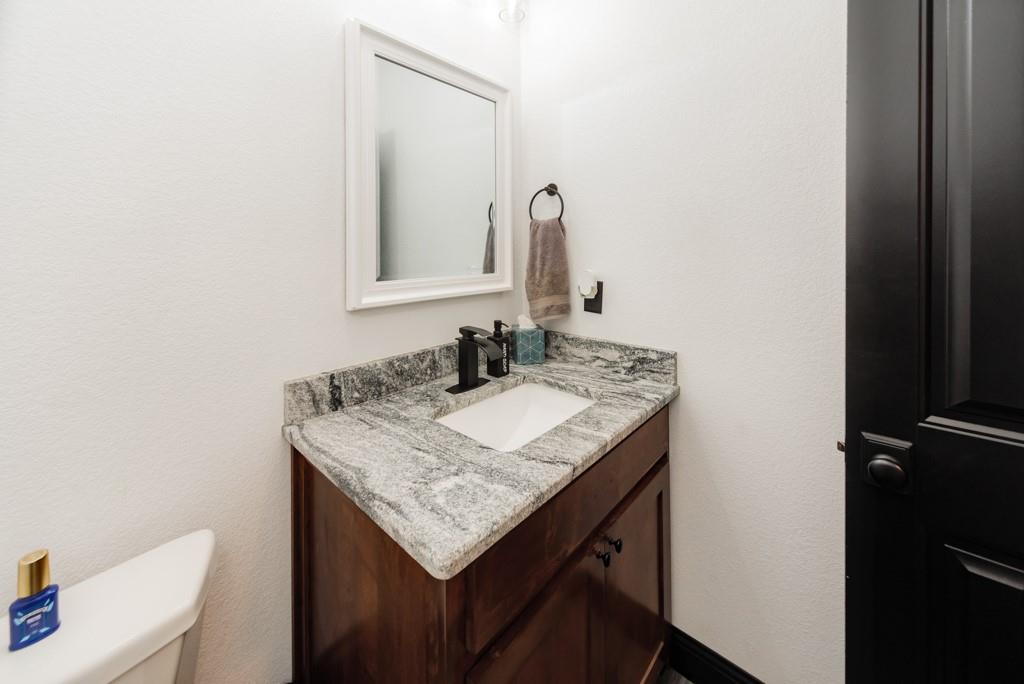 217 Polk Road Bowie, TX 76230 - Photo 19 of 39 a bathroom with a granite countertop sink and a mirror