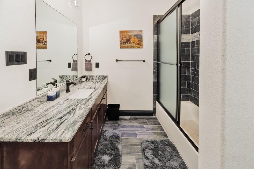 217 Polk Road Bowie, TX 76230 - Photo 26 of 39 a bathroom with a granite countertop sink a mirror and shower