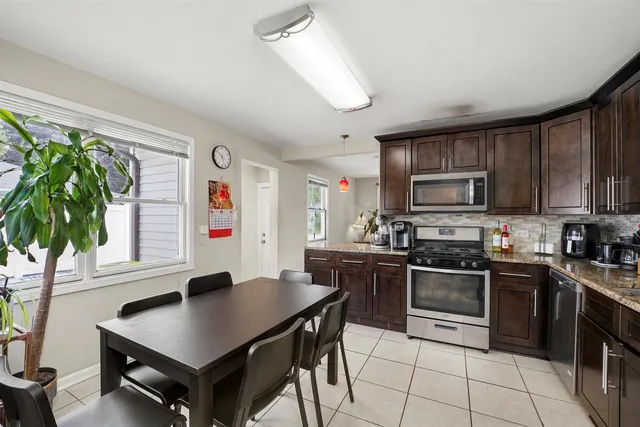 a kitchen with stainless steel appliances granite countertop a stove top oven a sink dishwasher a dining table and chairs with wooden floor