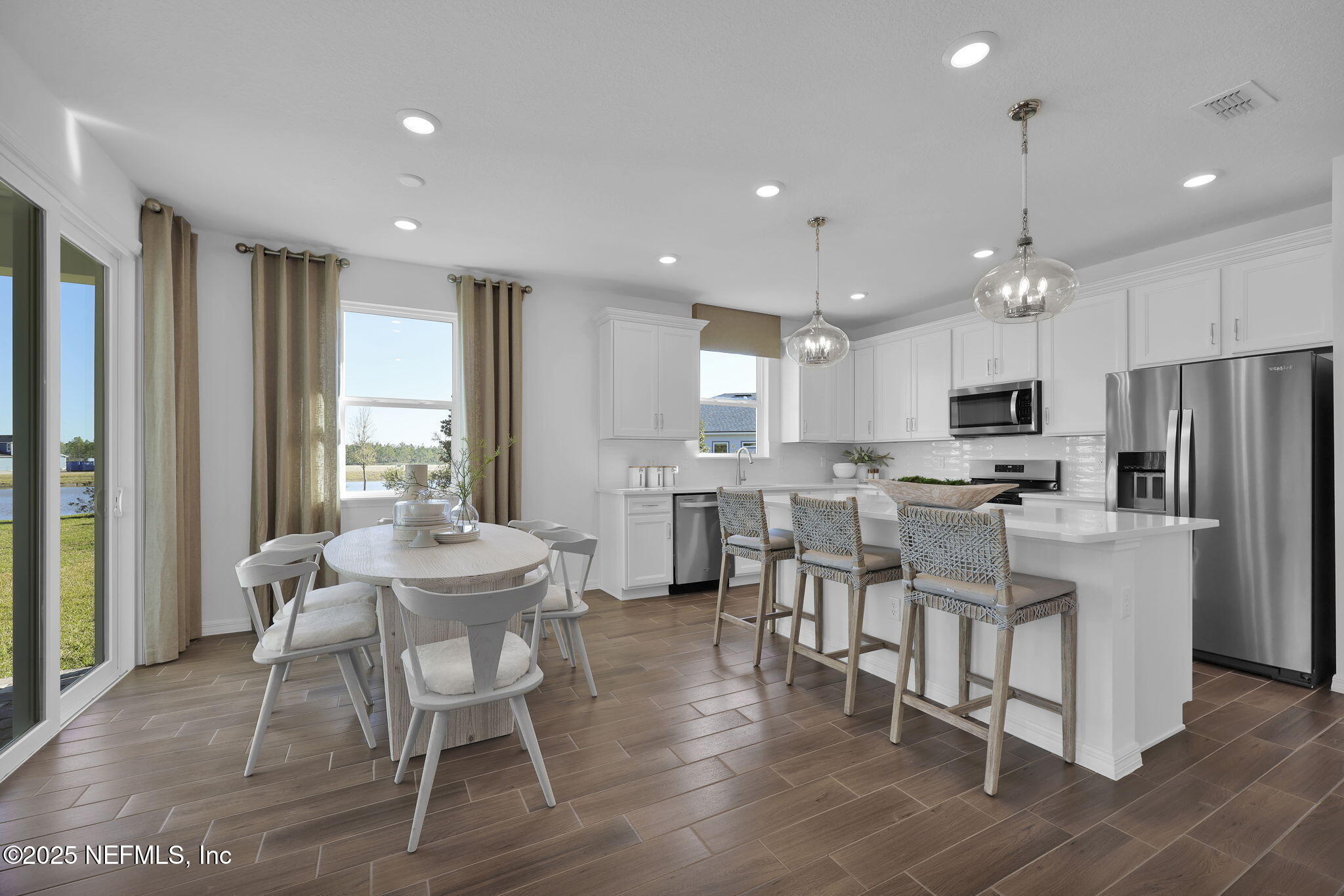 1745 Mickey Way Middleburg, FL 32068 - Photo 16 of 30 a kitchen with stainless steel appliances kitchen island granite countertop a dining table chairs refrigerator and sink