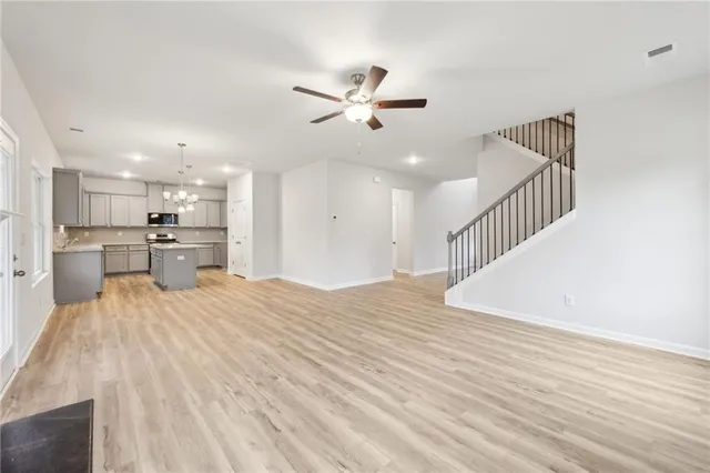 a view of a kitchen with kitchen island a sink wooden floor and stainless steel appliances