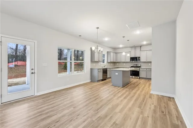 a kitchen with stainless steel appliances granite countertop a stove top oven a sink dishwasher a refrigerator and white cabinets with wooden floor