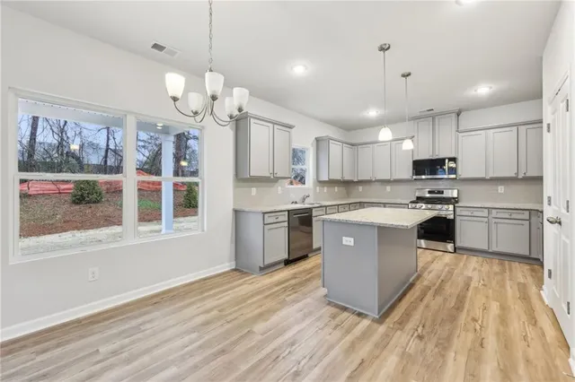 a kitchen with kitchen island granite countertop wooden floors stainless steel appliances a sink and cabinets
