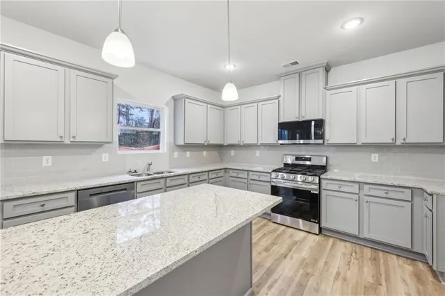 a kitchen with stainless steel appliances granite countertop a sink a stove top oven a counter space and cabinets