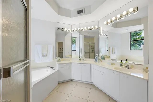 a spacious bathroom with a double vanity sink mirror and bathtub