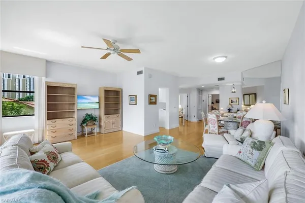 a living room with furniture kitchen view and a large window