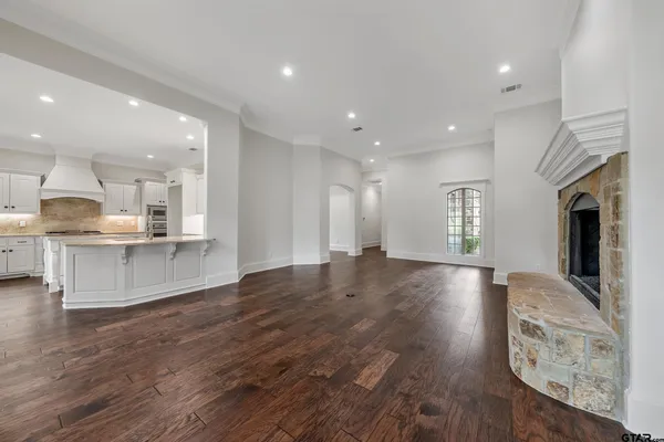 a view of an empty room with wooden floor and a fireplace