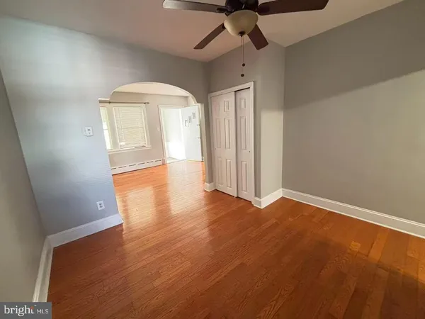 an empty room with wooden floor fan and windows