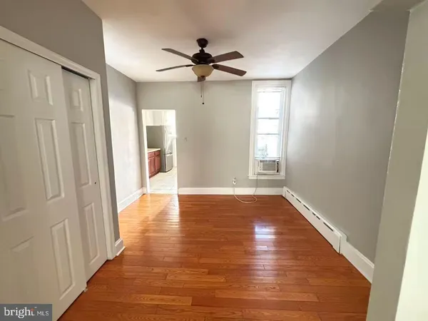 a view of empty room with wooden floor and fan