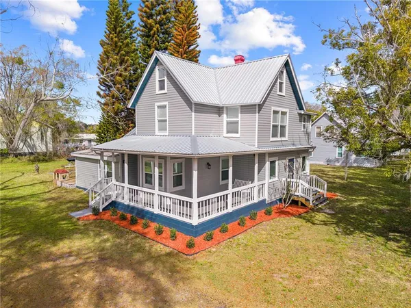 a view of a white house with large windows and a small yard