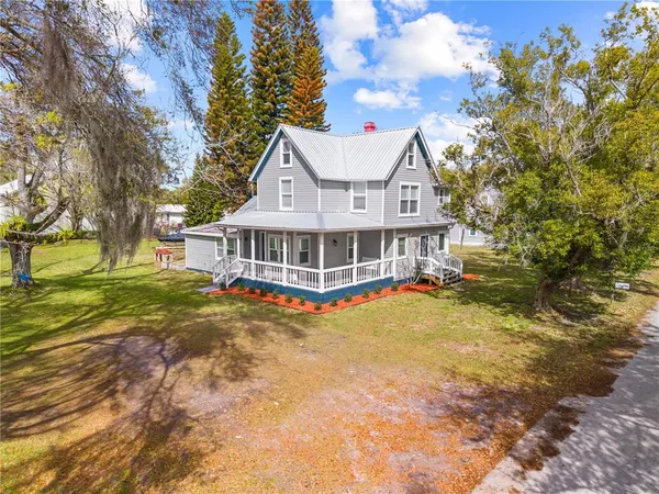 a view of a house with a big yard and large trees