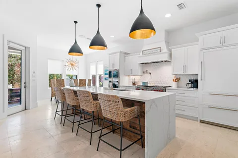 a kitchen with stainless steel appliances granite countertop a stove a sink a refrigerator a dining table and chairs with wooden floor