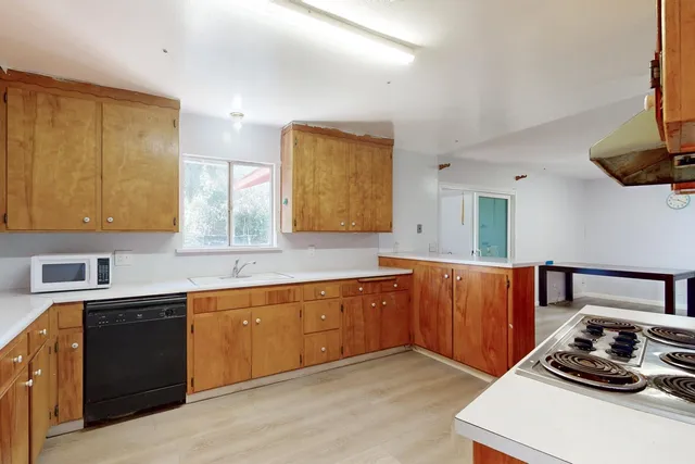 a kitchen with stainless steel appliances a sink cabinets and wooden floor