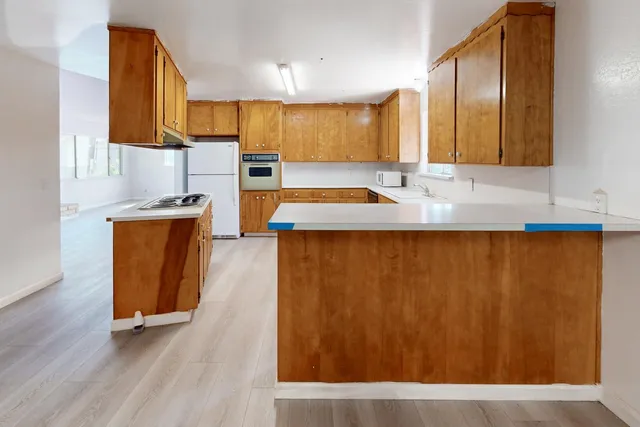 a view of an empty room with wooden floor and a bathroom