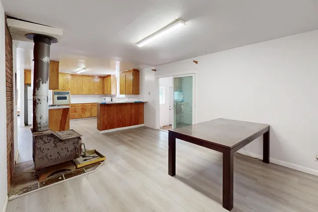 a view of an empty room with wooden floor and a bathroom