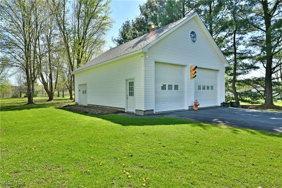 379 Housel Craft Road Bristolville, OH 44402 - Photo 4 of 50 View of home's exterior with a detached garage, an outdoor structure, a shingled roof, and a lawn