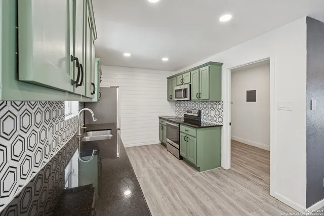 a kitchen with stainless steel appliances granite countertop a sink a stove and cabinets