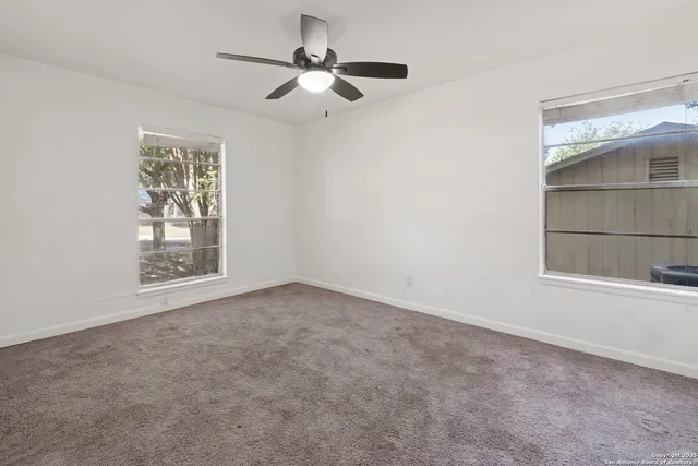 an empty room with a window and a fan