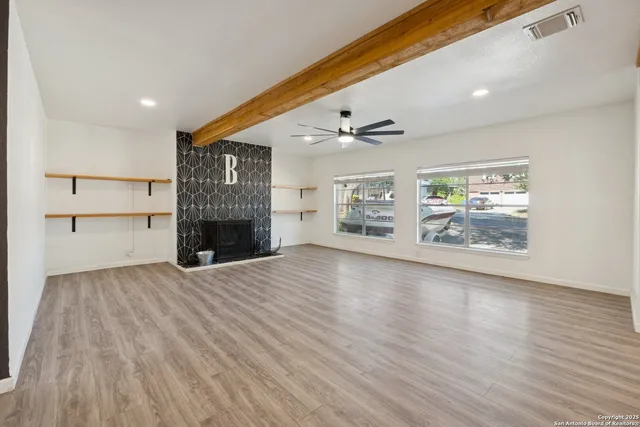 a view of empty room with wooden floor and fireplace