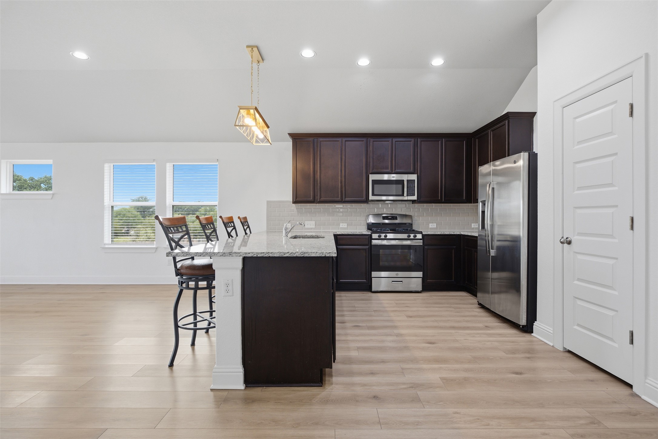321 Gaida Loop Georgetown, TX 78628 - Photo 12 of 26 Rich dark cabinetry and a central island ground this airy, open-concept kitchen.
