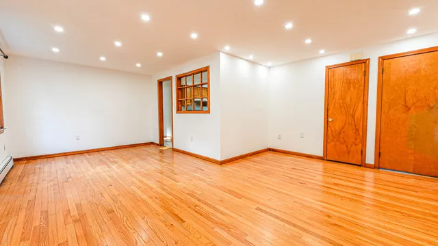 a view of an empty room with wooden floor and sliding window