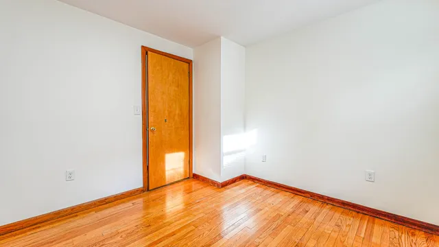 a view of empty room with wooden floor and small window