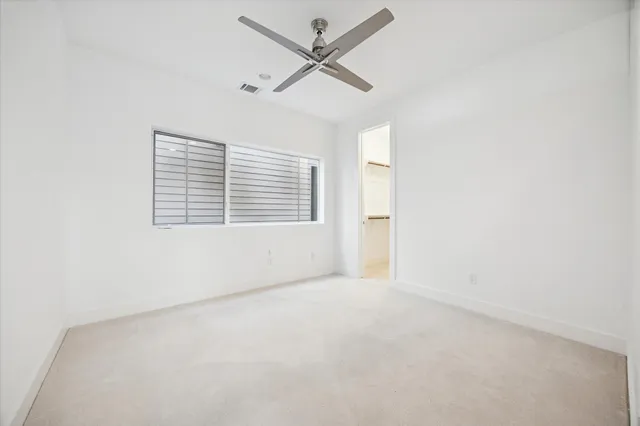 an empty room with a window and a fan