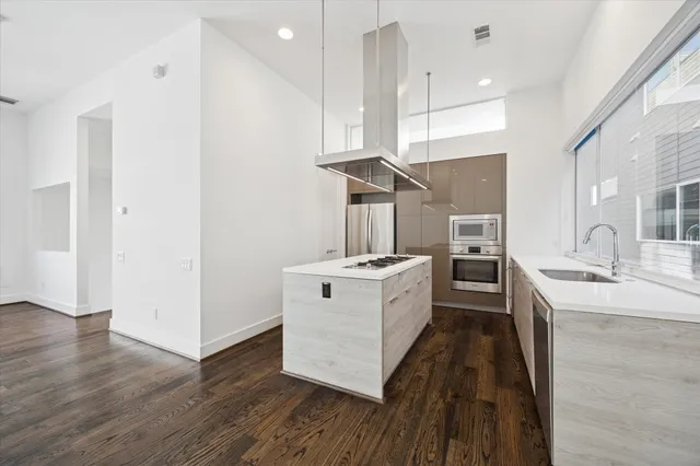 a large white kitchen with a stove a sink dishwasher and a refrigerator with wooden floor